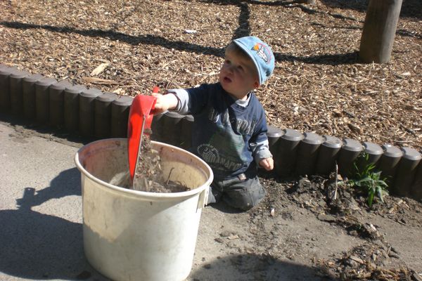 Kinder und Eltern bei der Gartenarbeit auf dem Schulhof
